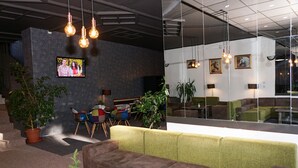A modern lobby with seating areas, a TV screen, and hanging lights. - Hotel Bor (Samokov)