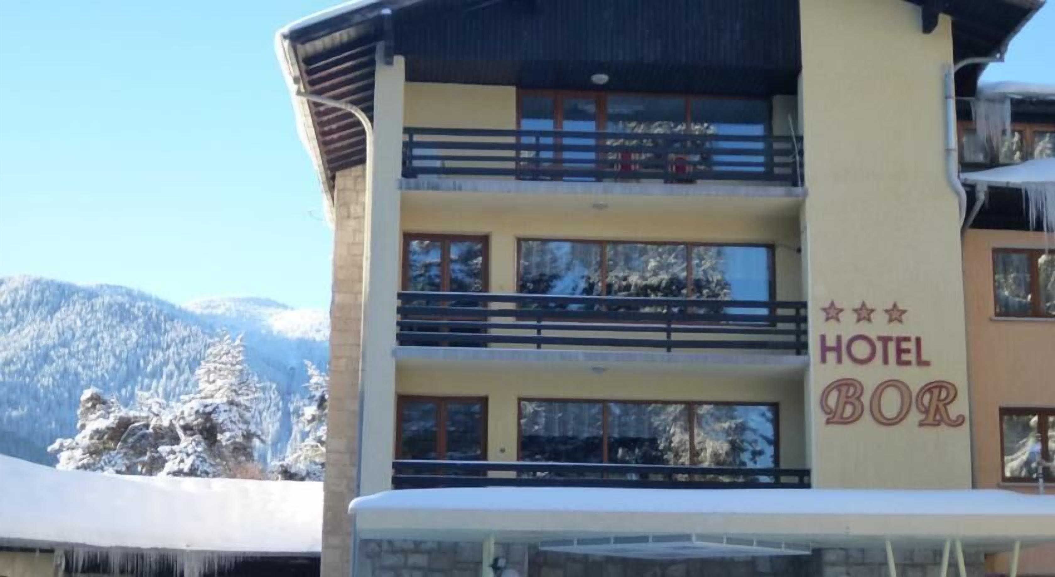 Un hotel de varios pisos con balcones y vistas a montañas nevadas.