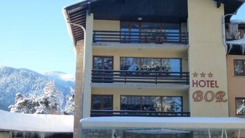 Un hotel de varios pisos con balcones y vistas a montañas nevadas.