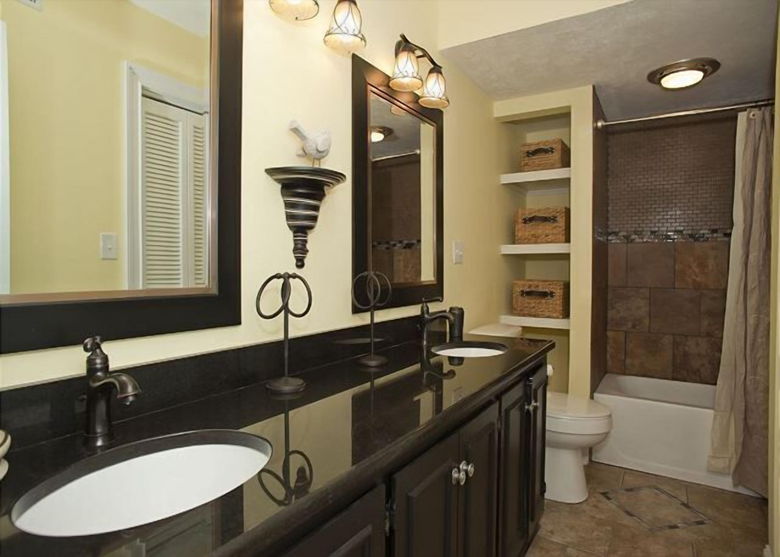 A bathroom with two sinks, a large mirror, and a shower area.
