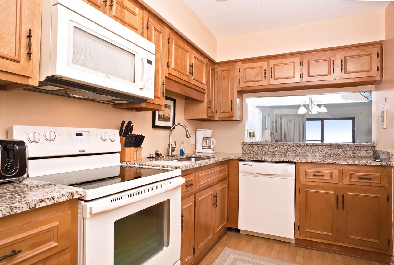 A kitchen with wooden cabinets, a microwave, a stove, a dishwasher, and a coffee maker.
