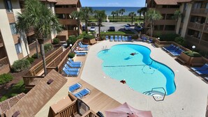 A hotel with a pool, lounge chairs, and a view of the ocean.