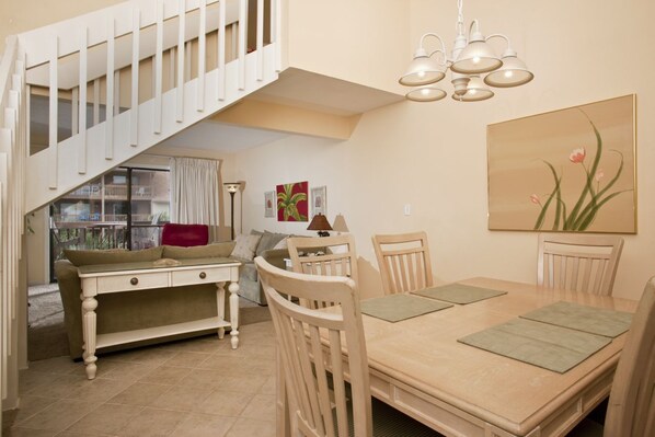 A dining area with a wooden table and chairs, a staircase with white railings, and a chandelier. - Anchorage I (Myrtle Beach)
