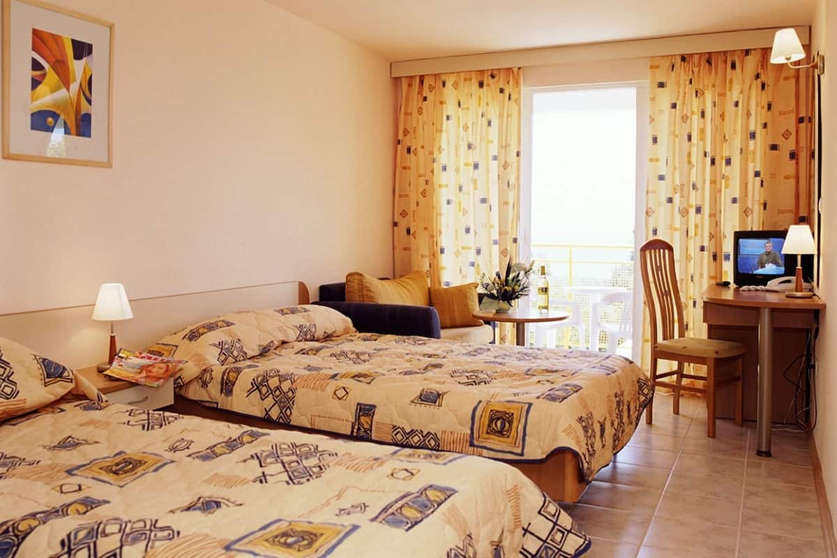 A hotel room with two beds, a desk with a computer, and a chair.