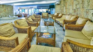 Un vestíbulo con mobiliario de mimbre, una mesa de centro de vidrio y paredes de piedra.