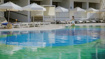 En sÀsongsöppen utomhuspool, parasoller och solstolar