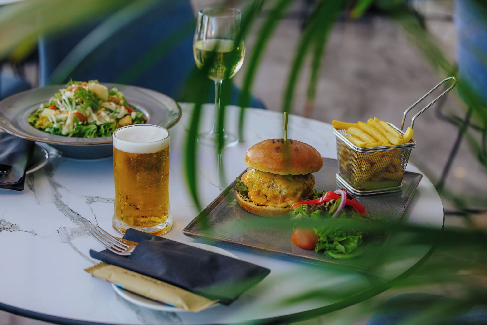 A meal consisting of a burger, fries, and a salad on a marble table.