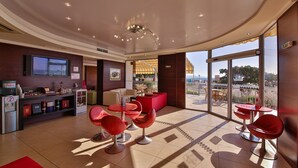 A modern hotel lobby with a bar area, seating, and a view of the beach. - Hotel Kaliakra Beach - Ultra All Inclusive (Albena)