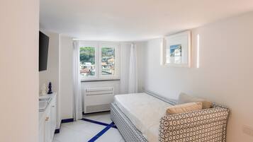 A bedroom with a bed, a window, a radiator, a desk, and a picture on the wall.