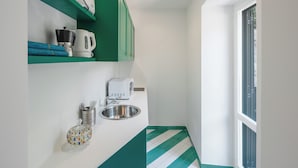 Cocina compacta con lavamanos, hervidor de agua, microondas y tostadora.