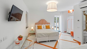 Un dormitorio moderno con cama, mesitas de noche, televisión y un ventanal grande.