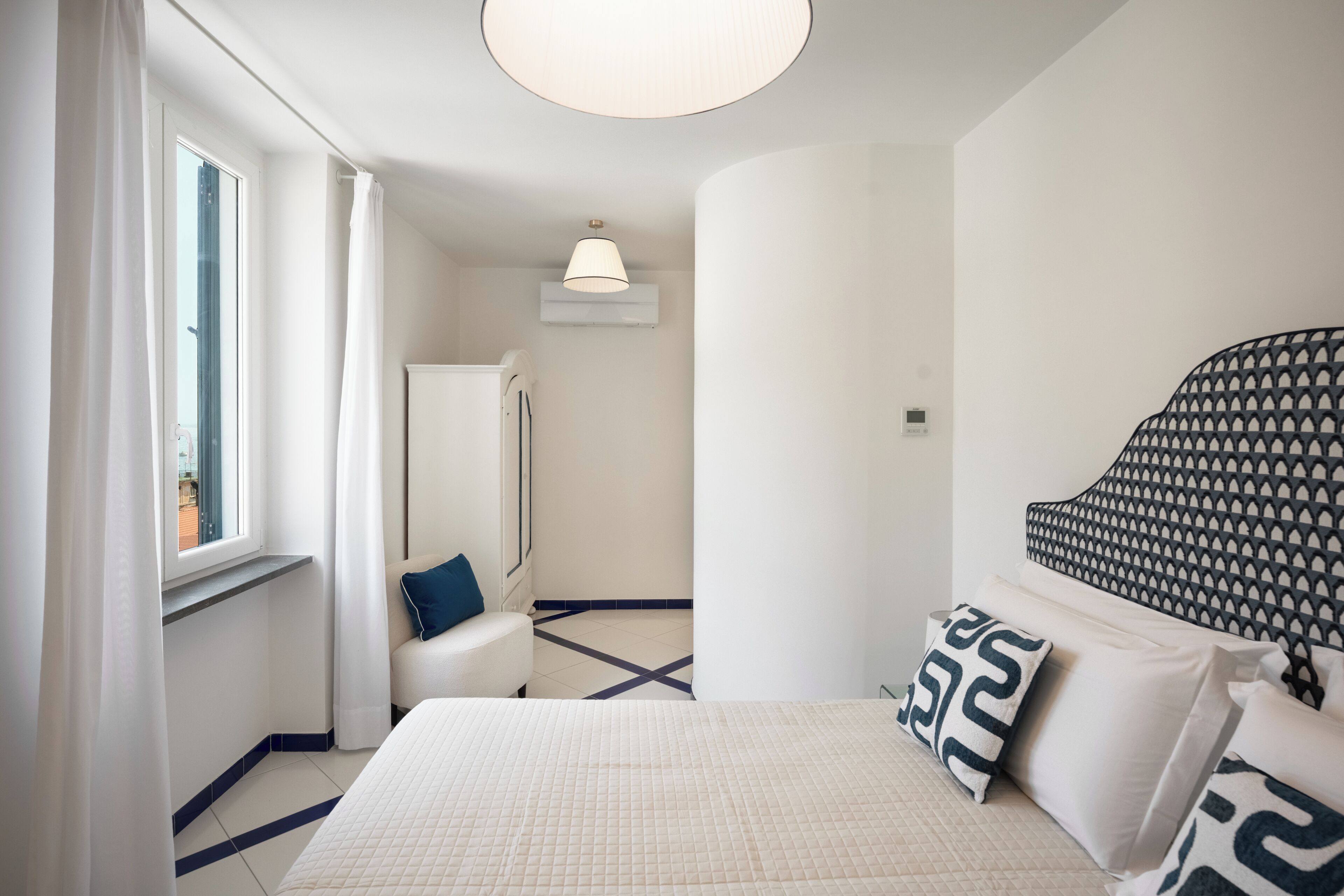 A hotel room with a large bed, a chair, a desk, and a window.