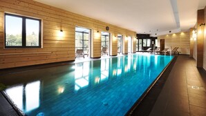 A large indoor swimming pool with wooden walls and multiple windows.