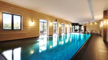Una piscina techada, sillones reclinables de piscina