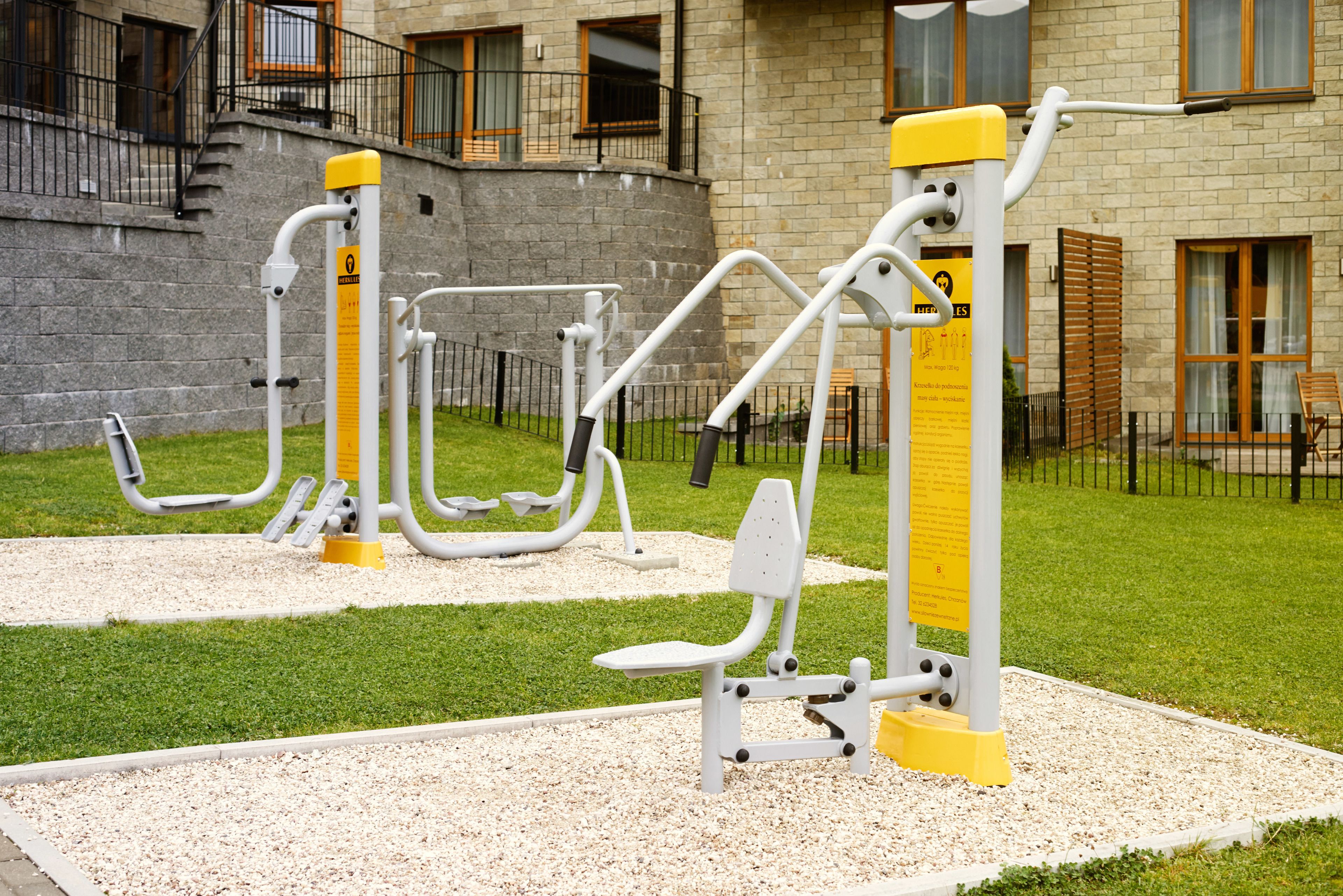 Outdoor exercise equipment in a courtyard with a building in the background.