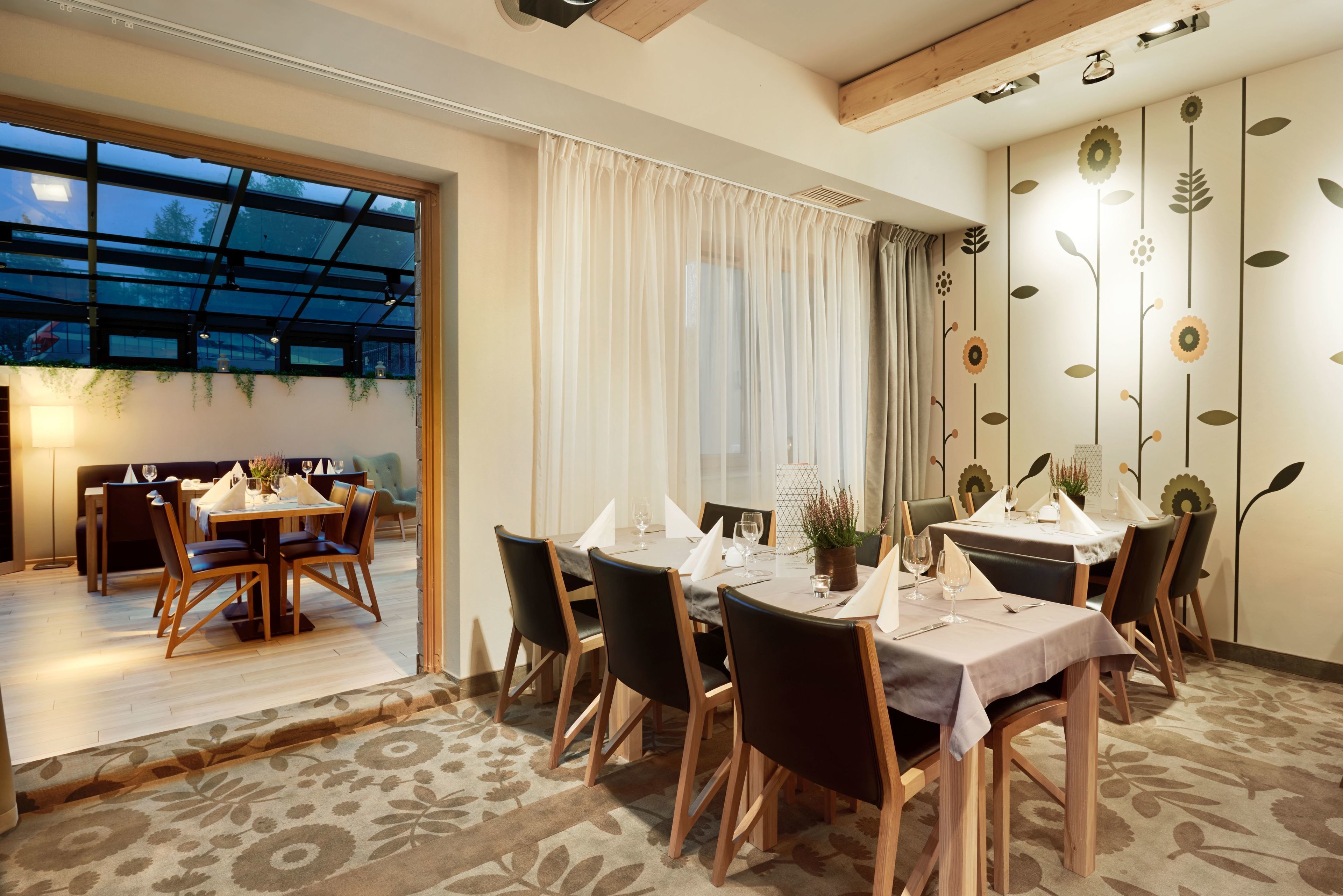 A dining area with a table set for six, wooden chairs, and a view through a glass door to an outdoor seating area.