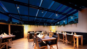 A restaurant with a glass ceiling, wooden tables, and chairs.