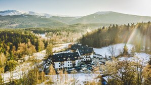 A large, multi-story hotel with a symmetrical facade, surrounded by snow-covered terrain and dense forests.