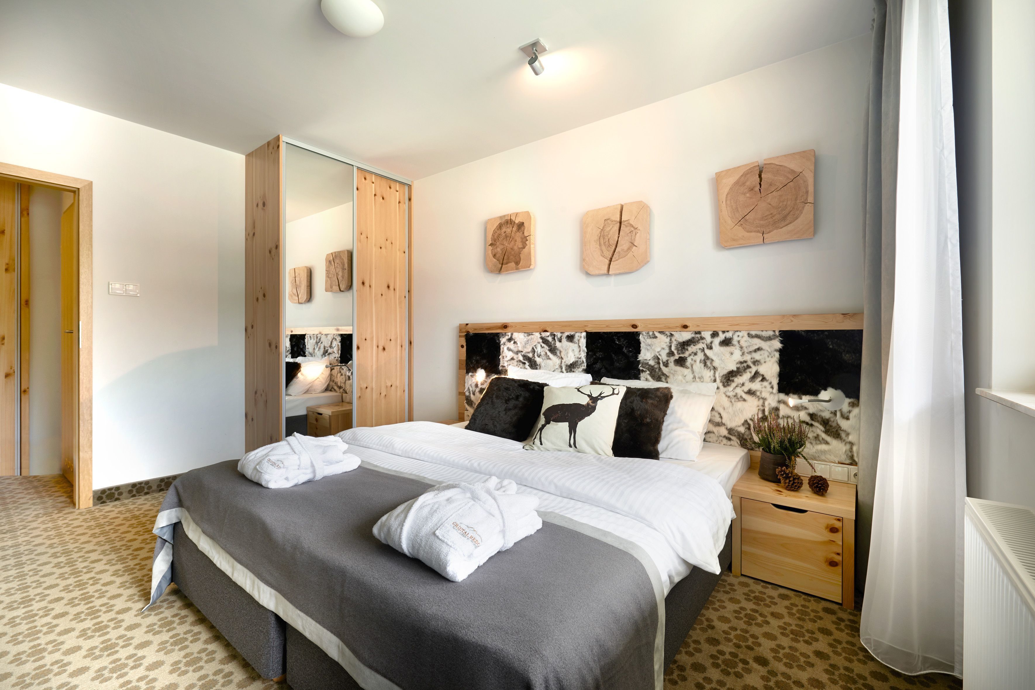 Un dormitorio moderno con una cama grande, un armario de madera y un espejo.