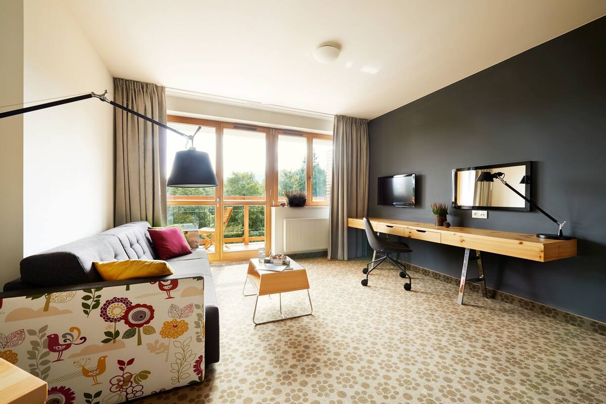 Une chambre moderne avec un canapé, un bureau et une grande fenêtre.