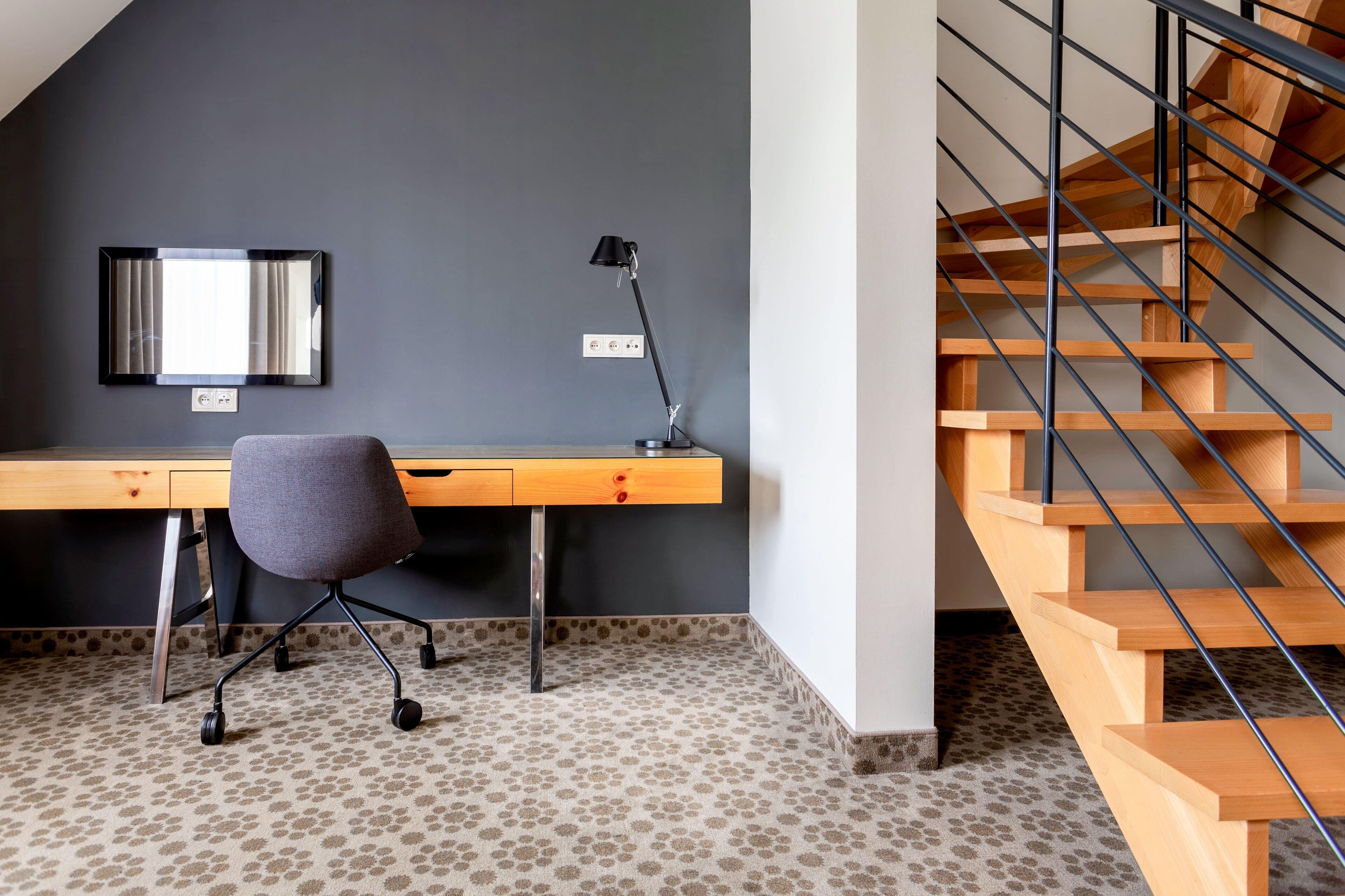 A modern office space with a desk, chair, and a spiral staircase.