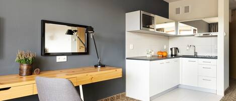 A compact kitchen with white cabinets, a microwave, and a coffee maker.