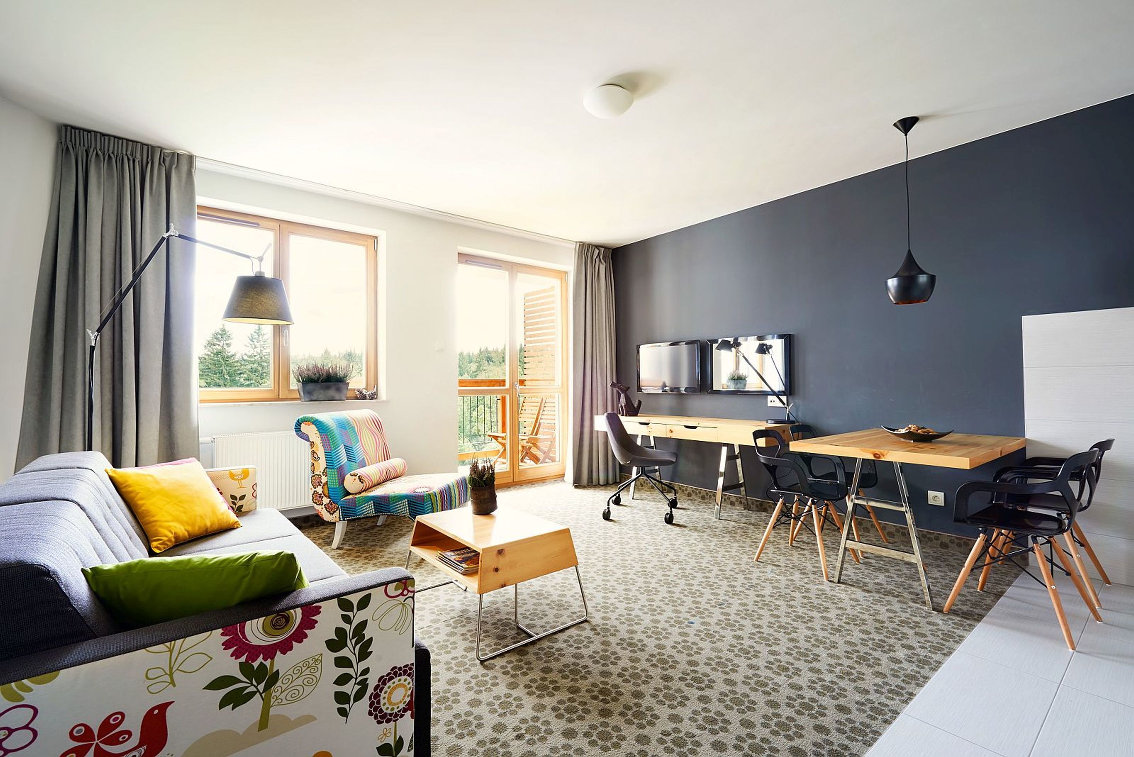 A modern living room with a sofa, a wooden desk, and a dining table with chairs.
