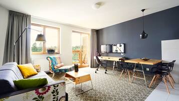 A modern living room with a sofa, a wooden desk, and a dining table with chairs.
