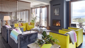 Een moderne lounge met zitgedeelte, een open haard en uitzicht op de omgeving.