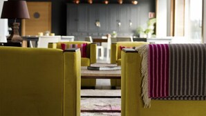 Een moderne woonkamer met gele fauteuils, een houten salontafel en een gestreept plaid.