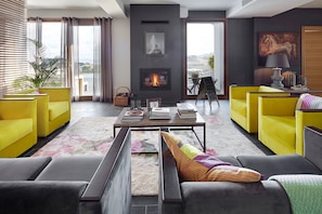Una sala de estar moderna con chimenea, sofás amarillos y vistas al exterior.