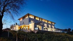 Een modern huis met twee verdiepingen, een balkon, grote ramen en een goed verlichte entree.