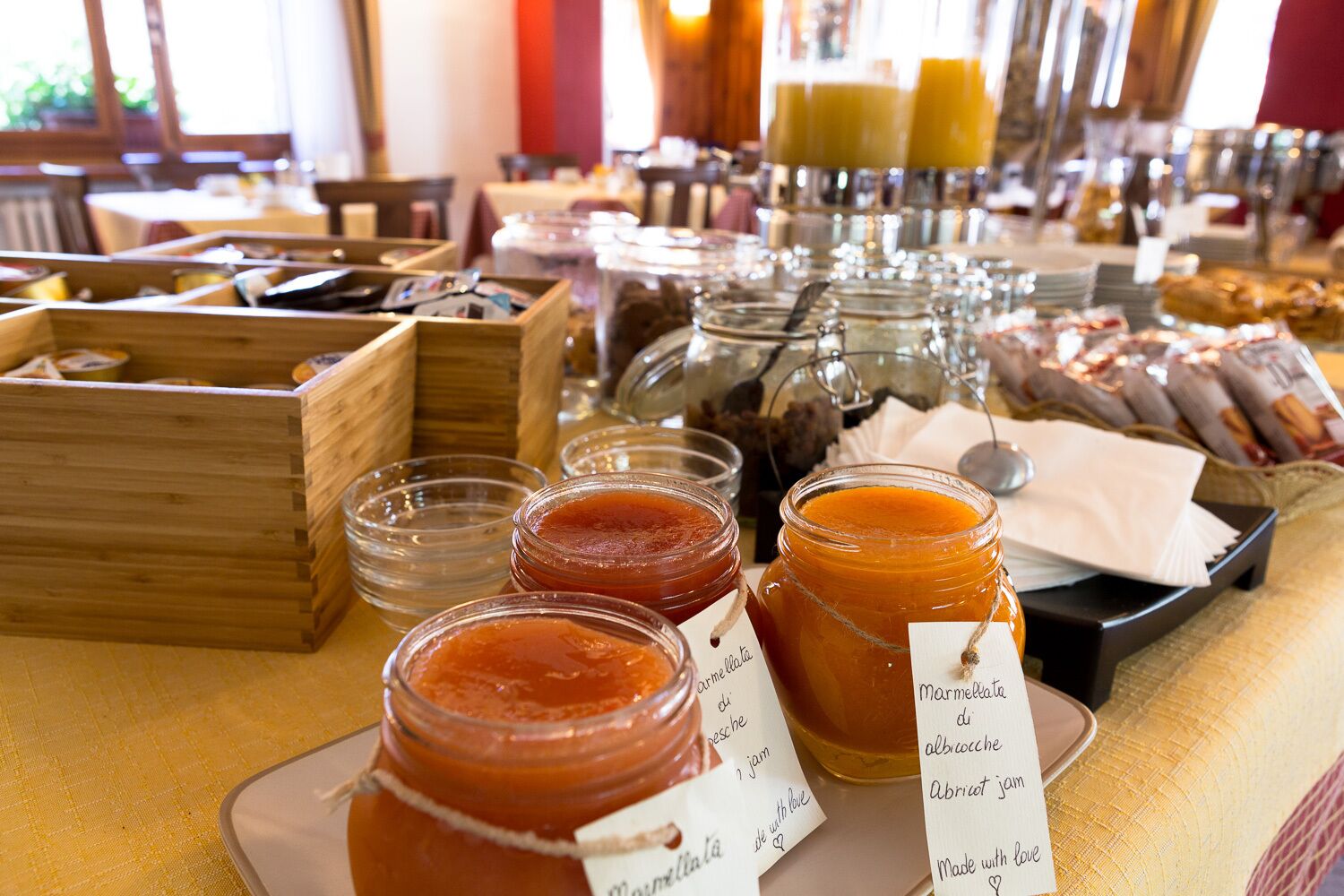 Una mesa de buffet con diversos alimentos y condimentos, incluyendo frascos de mermelada y confitura.