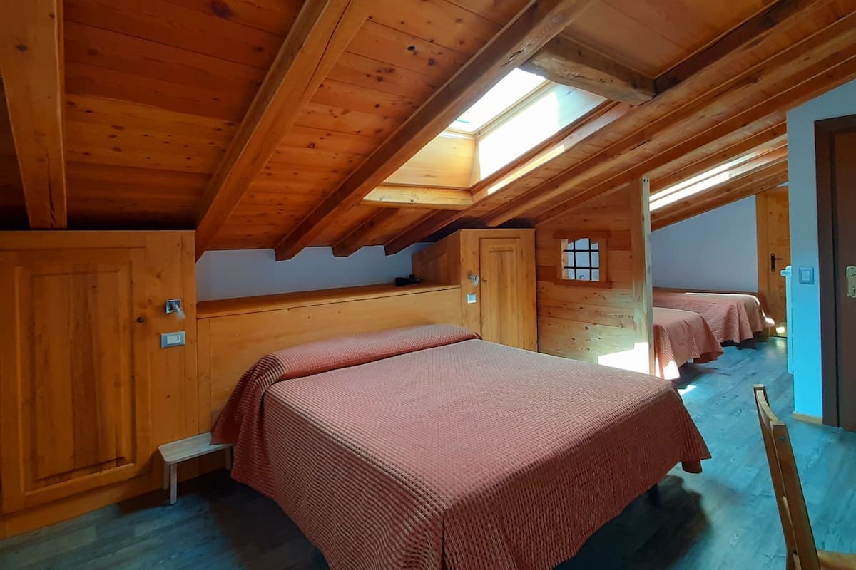 A wooden cabin with two beds, a skylight, and a small window.