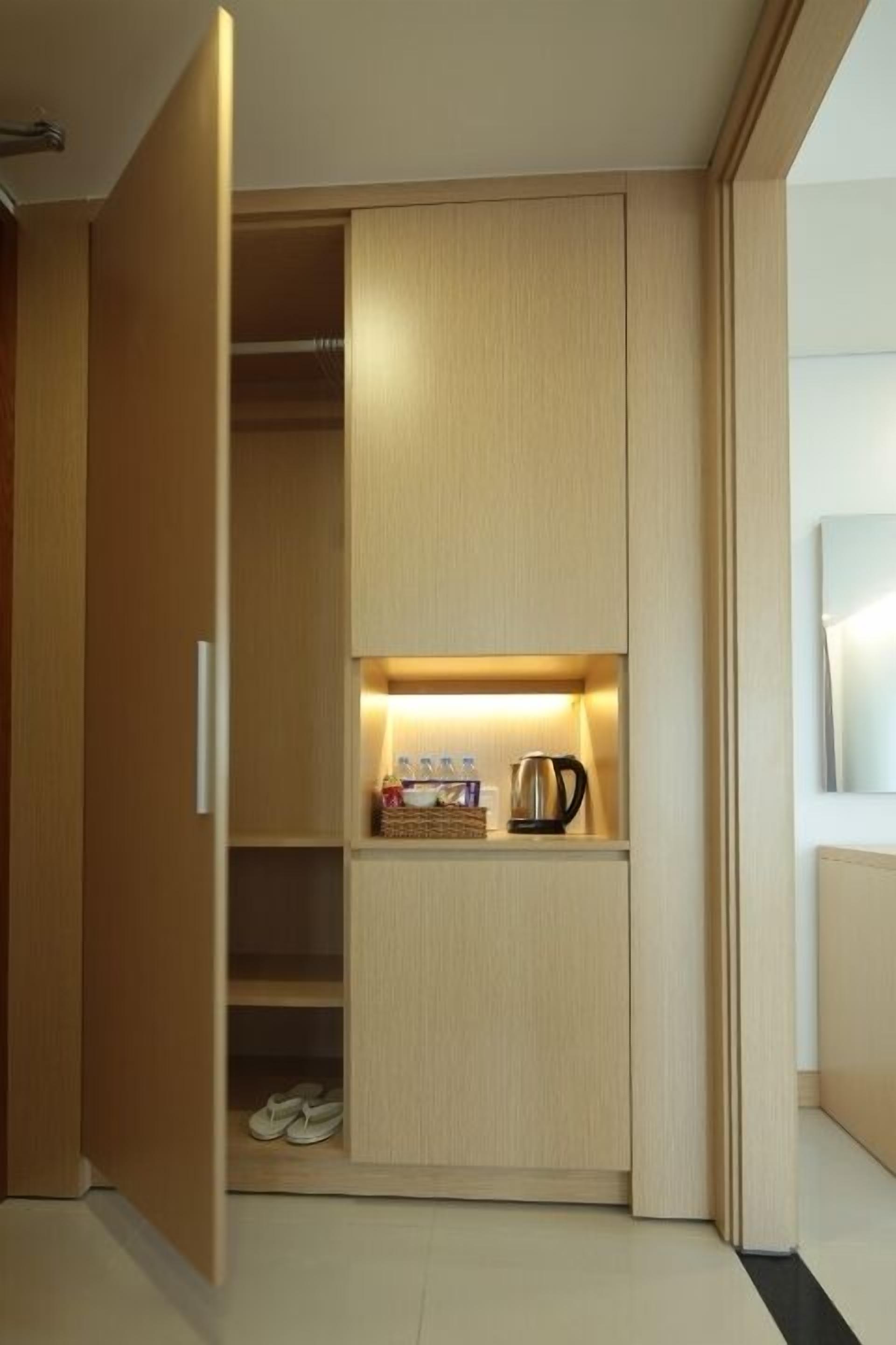A modern closet with built-in shelves and a shoe rack, containing a kettle, books, and a basket.