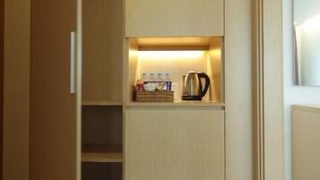 A modern closet with built-in shelves and a shoe rack, containing a kettle, books, and a basket.