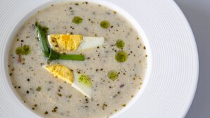 A white plate with a creamy soup garnished with green herbs and two halves of a boiled egg. - Q Hotel Kraków (Kraków)