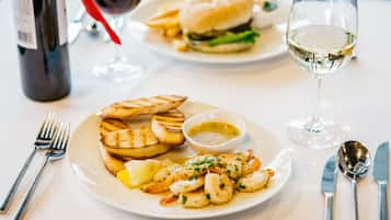 Una mesa de comedor con platos de comida, cubiertos y copas de vino.