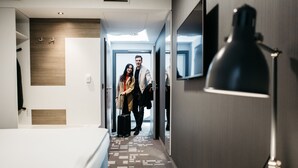 A hotel room with a bed, a desk, a lamp, and a mirror. There is a hallway leading to another room. - Q Hotel Kraków (Kraków)