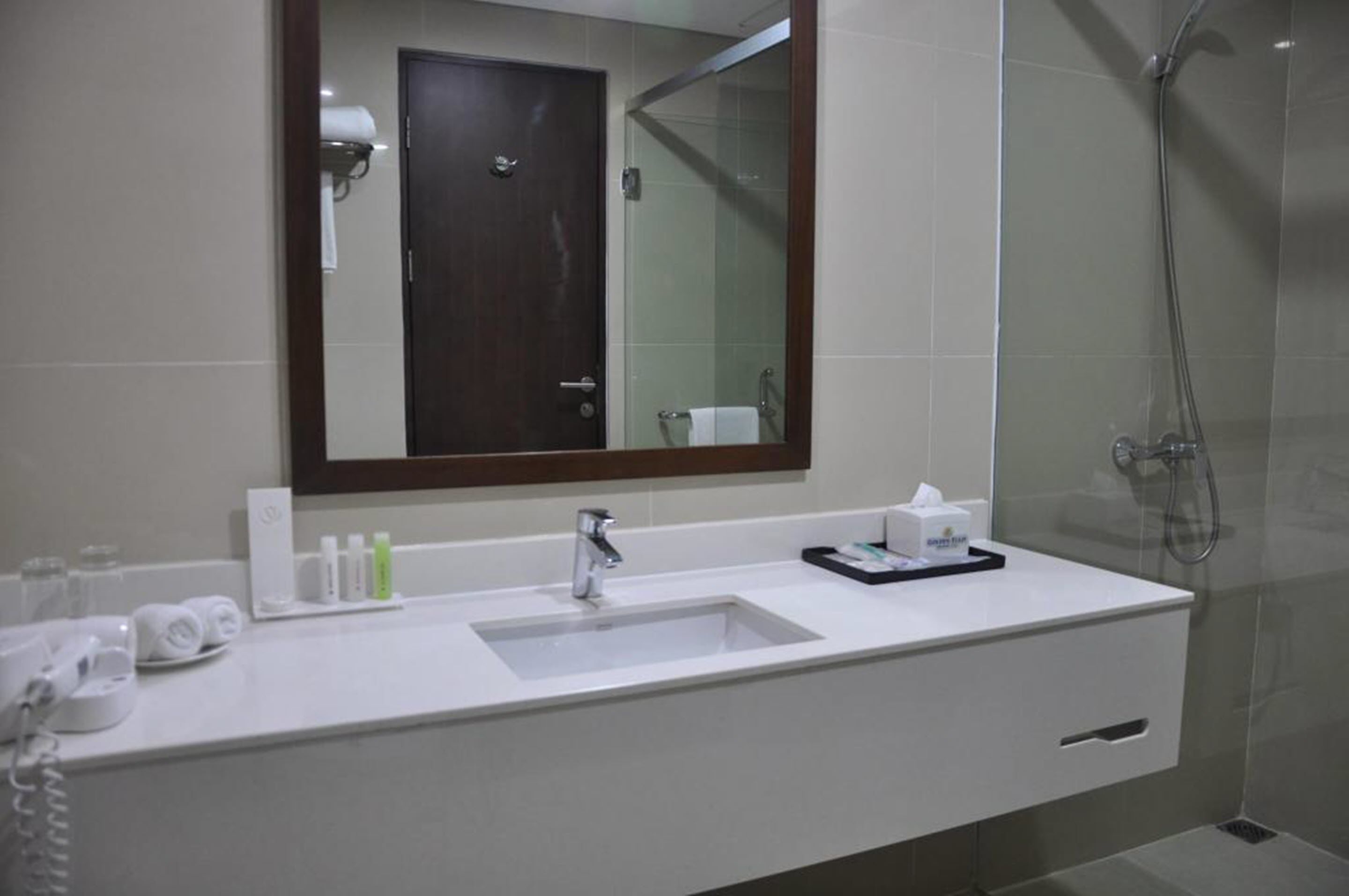 A modern bathroom with a large mirror, a sink, and a shower.