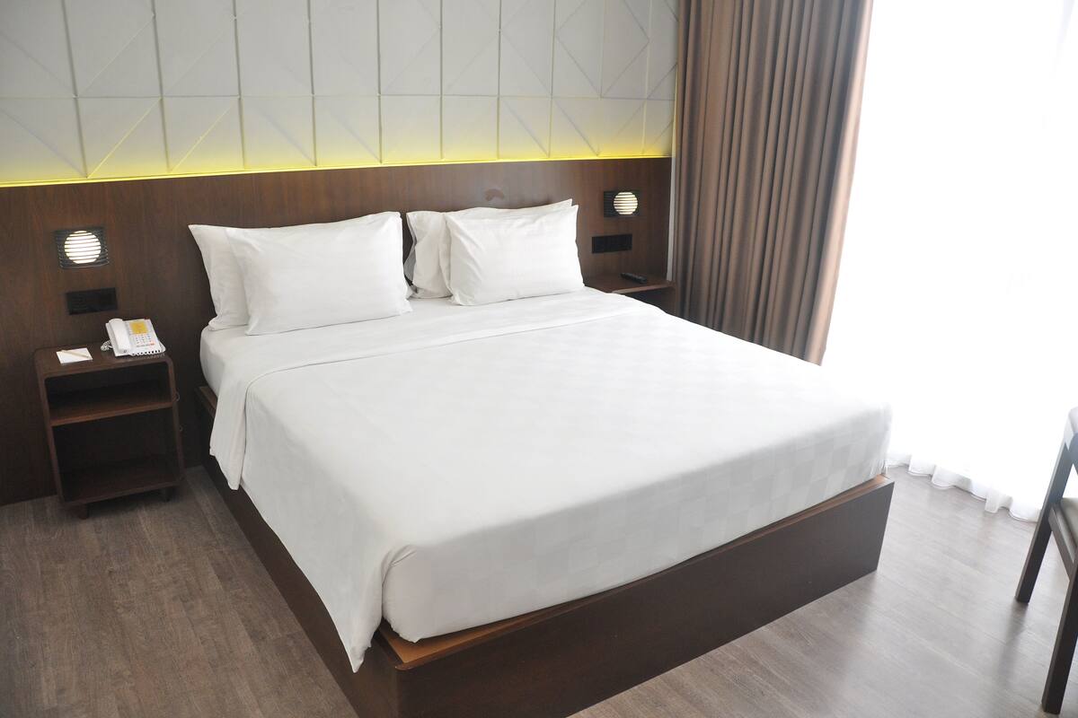 A neatly made bed with white linens in a hotel room.