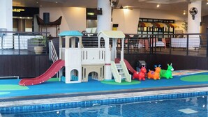 Un espace piscine intérieure comprenant une structure de jeux, des toboggans et des éléments de jeu colorés.