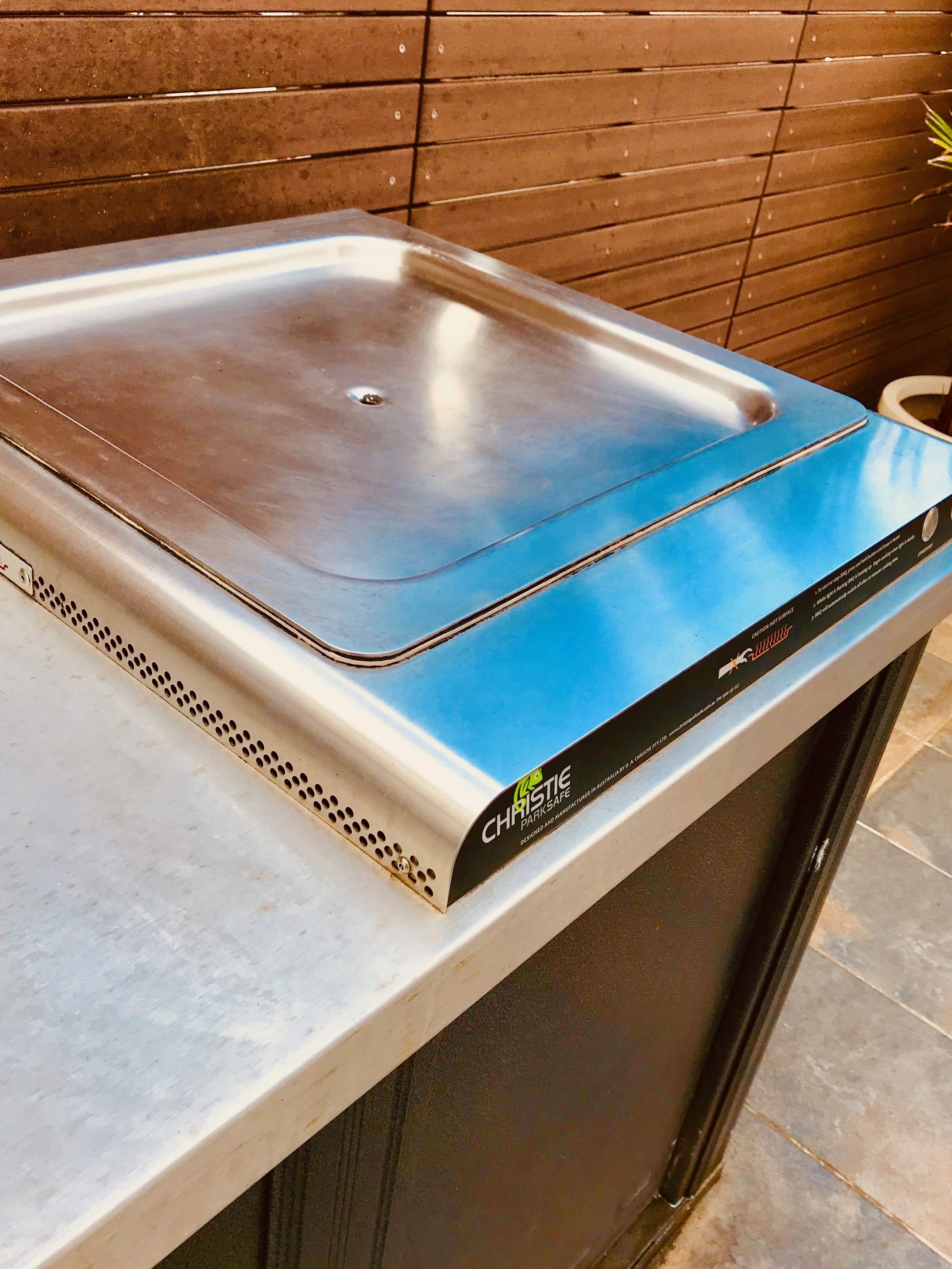 Una parrilla eléctrica portátil con una parte superior azul, etiquetada como "Christie Parksafe", sobre una encimera.