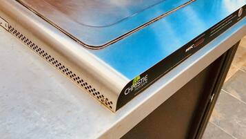 Una parrilla eléctrica portátil con una parte superior azul, etiquetada como "Christie Parksafe", sobre una encimera.