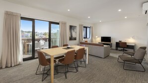 A modern hotel room with a dining area, a sofa, a TV, and a desk. - Quest Nowra (Nowra)