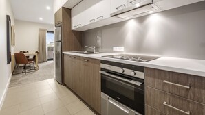 A modern kitchen with stainless steel appliances, wooden cabinets, and a white countertop. - Quest Nowra (Nowra)