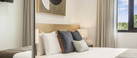 A modern hotel room with a large bed, a bedside table, a flat-screen TV, and a window with curtains.