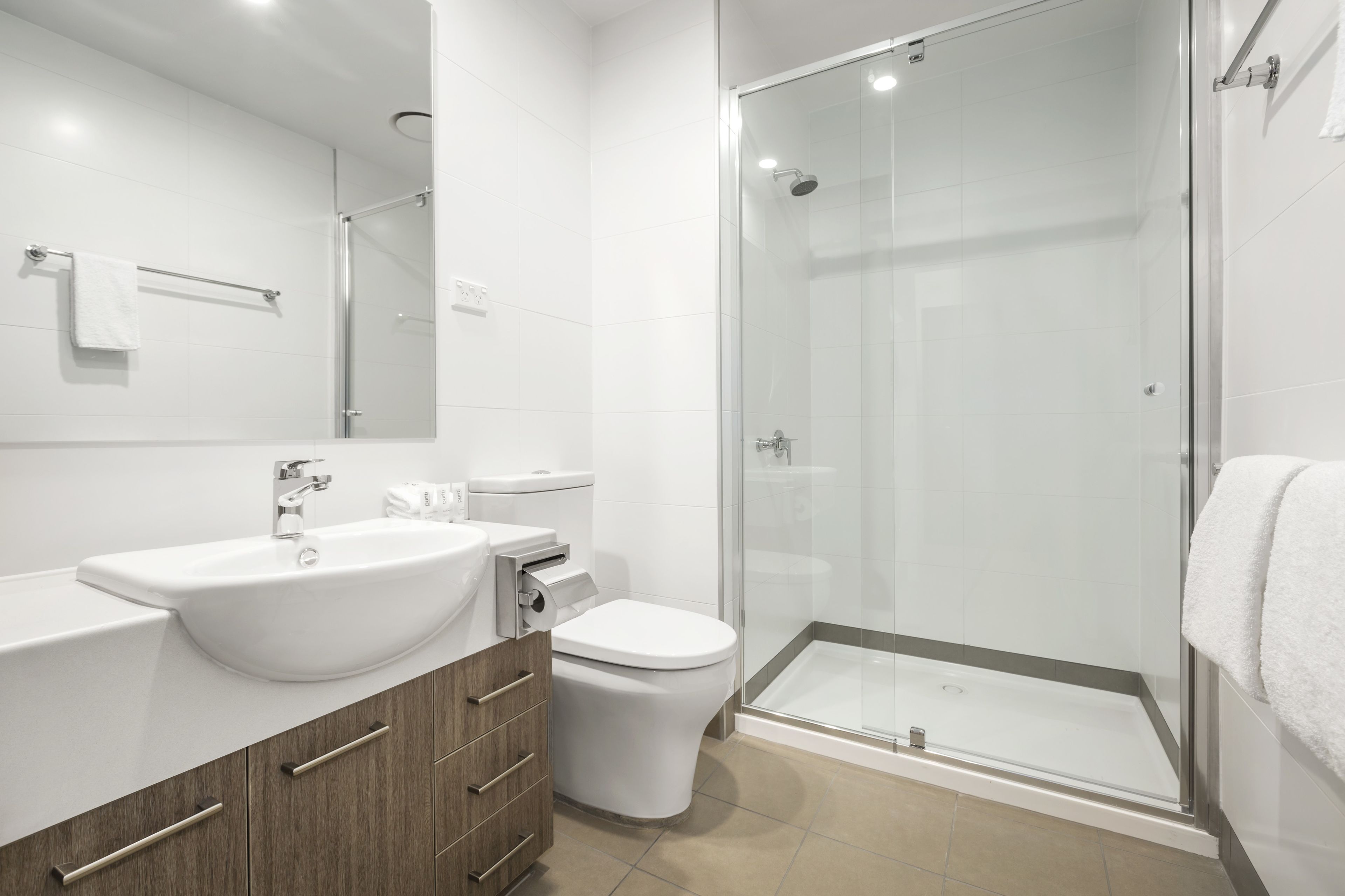 A modern bathroom with a glass-enclosed shower, a white sink, and a toilet.