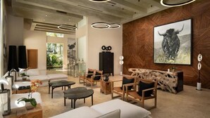 A modern living room with a large bull painting, wooden furniture, and circular ceiling lights. - Gansevoort Dominican Republic (Sosua)