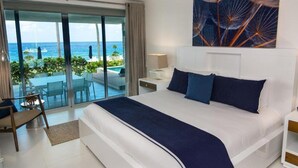 A hotel room with a large bed, a view of the ocean, and a dining area with outdoor seating. - Gansevoort Dominican Republic (Sosua)